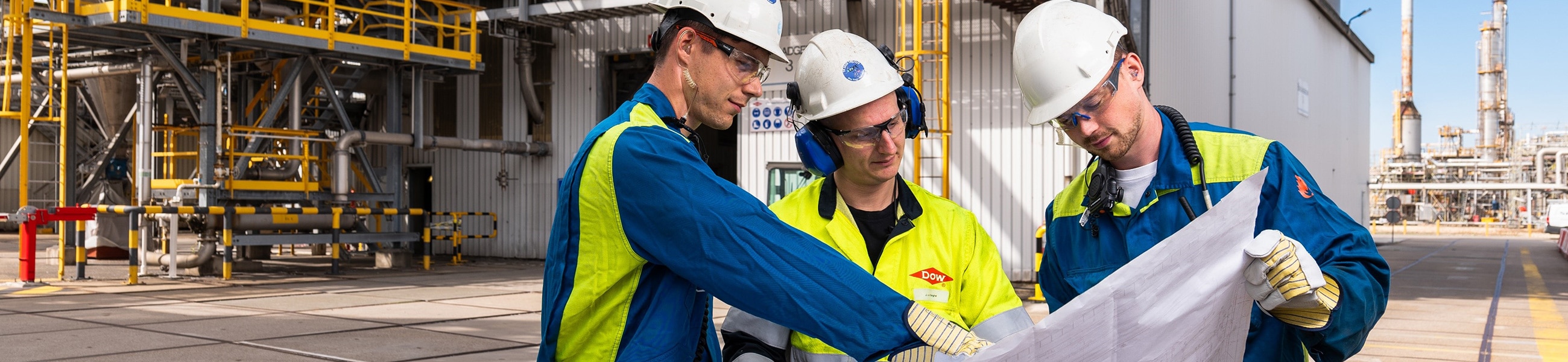 3 colleagues look at blueprints in the plant