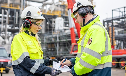Two colleagues in a plant look at a piece of paper